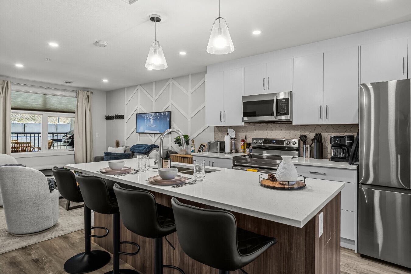 A modern kitchen with a central island, stainless steel appliances, and a large window.