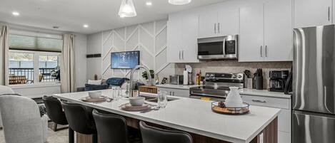 A modern kitchen with a central island, stainless steel appliances, and a large window.