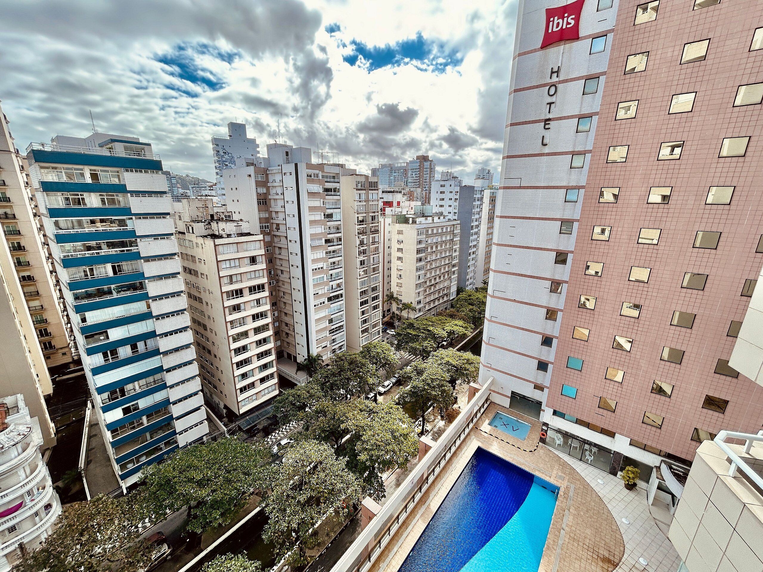 Un hôtel de grande hauteur, avec de nombreux étages, une piscine sur le toit et de nombreux espaces verts environnants.