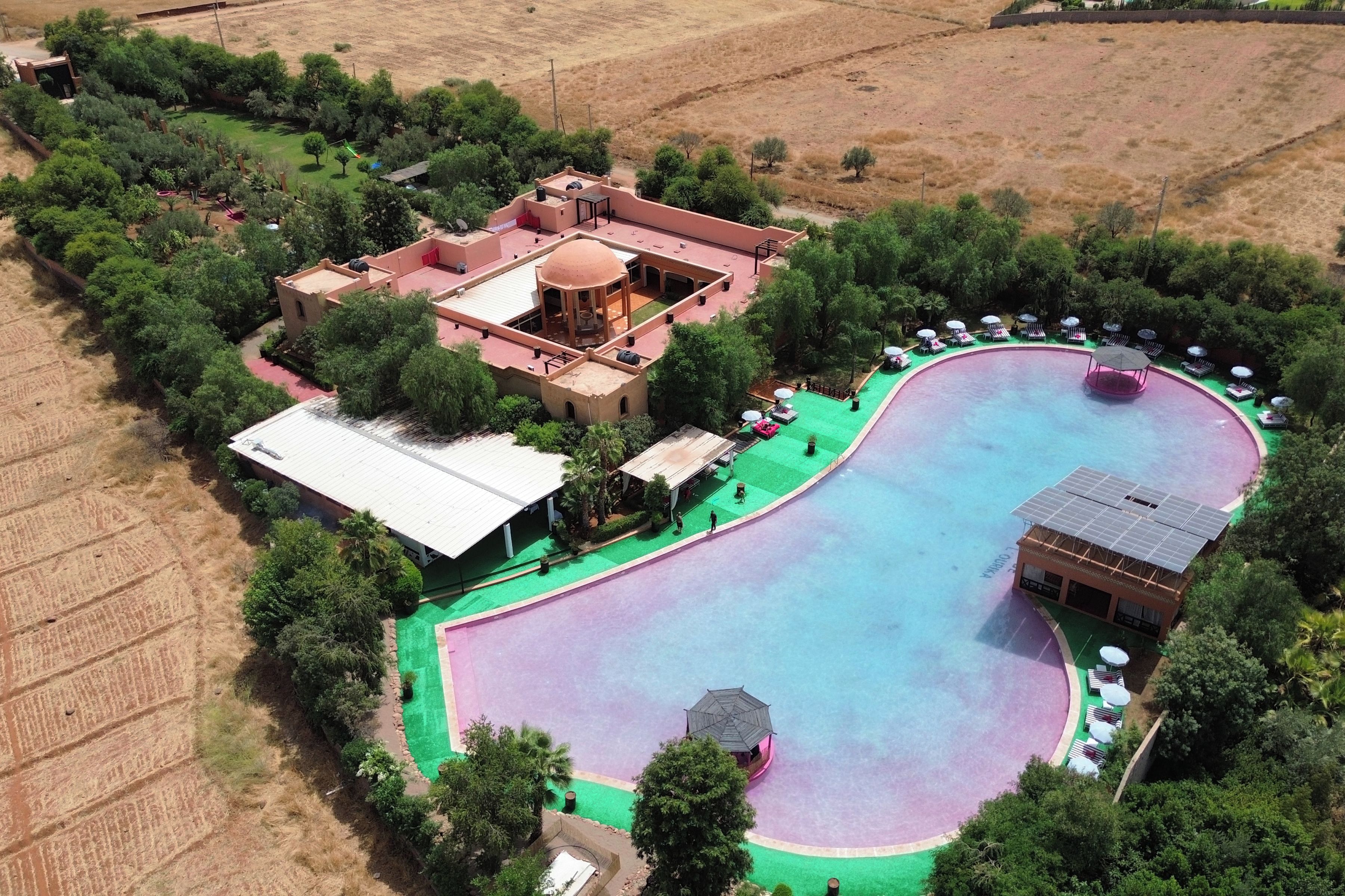 An aerial view of a resort with a swimming pool, a gazebo, and a covered outdoor area.