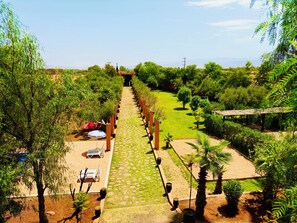 A pathway leading to a building with a covered seating area and a car parked nearby. - HOTEL BOUTIQUE PINK LAGOON (Ghmate)