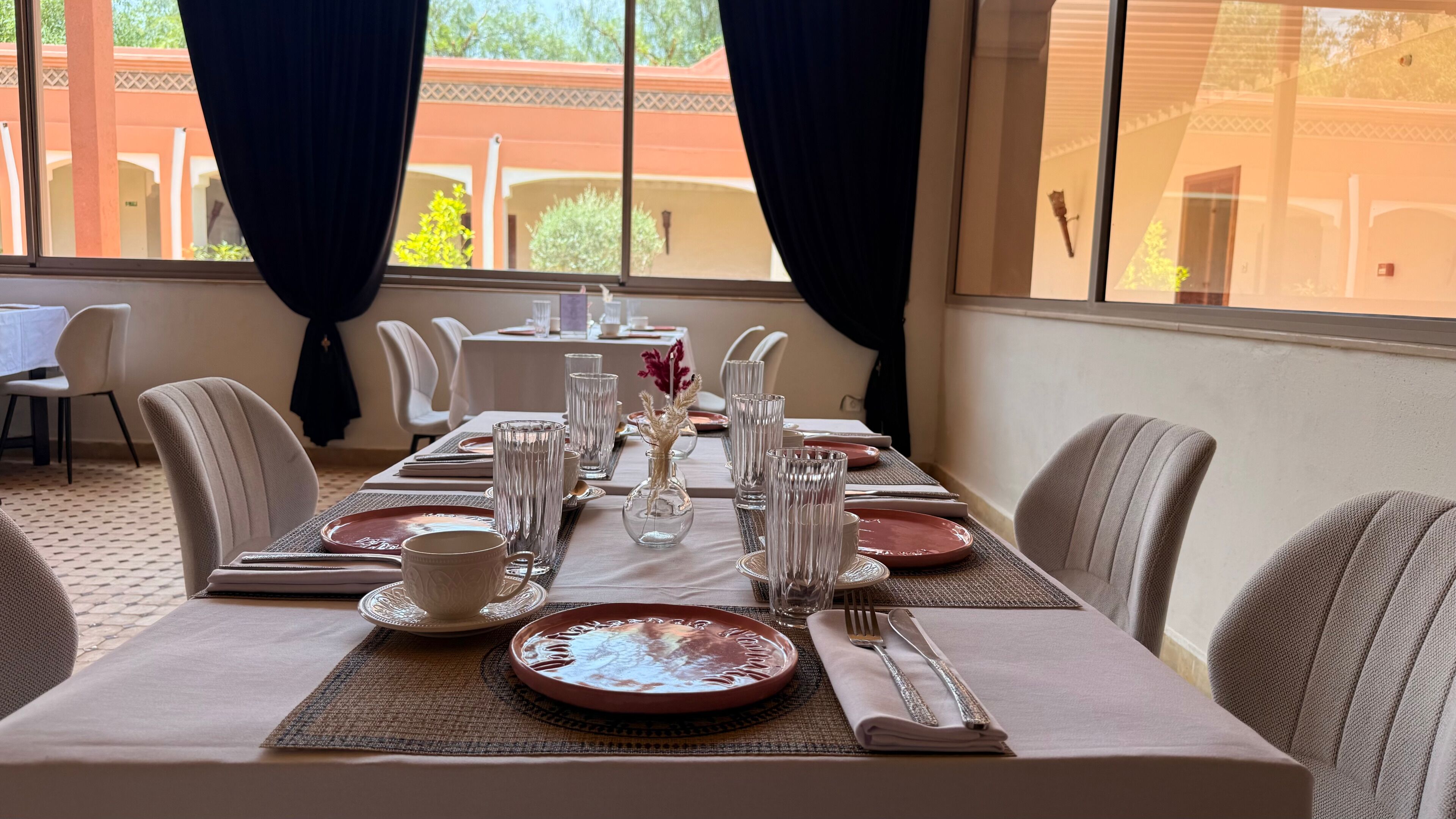 Une table à manger dressée pour quatre personnes, avec vue sur un bâtiment à l’extérieur.