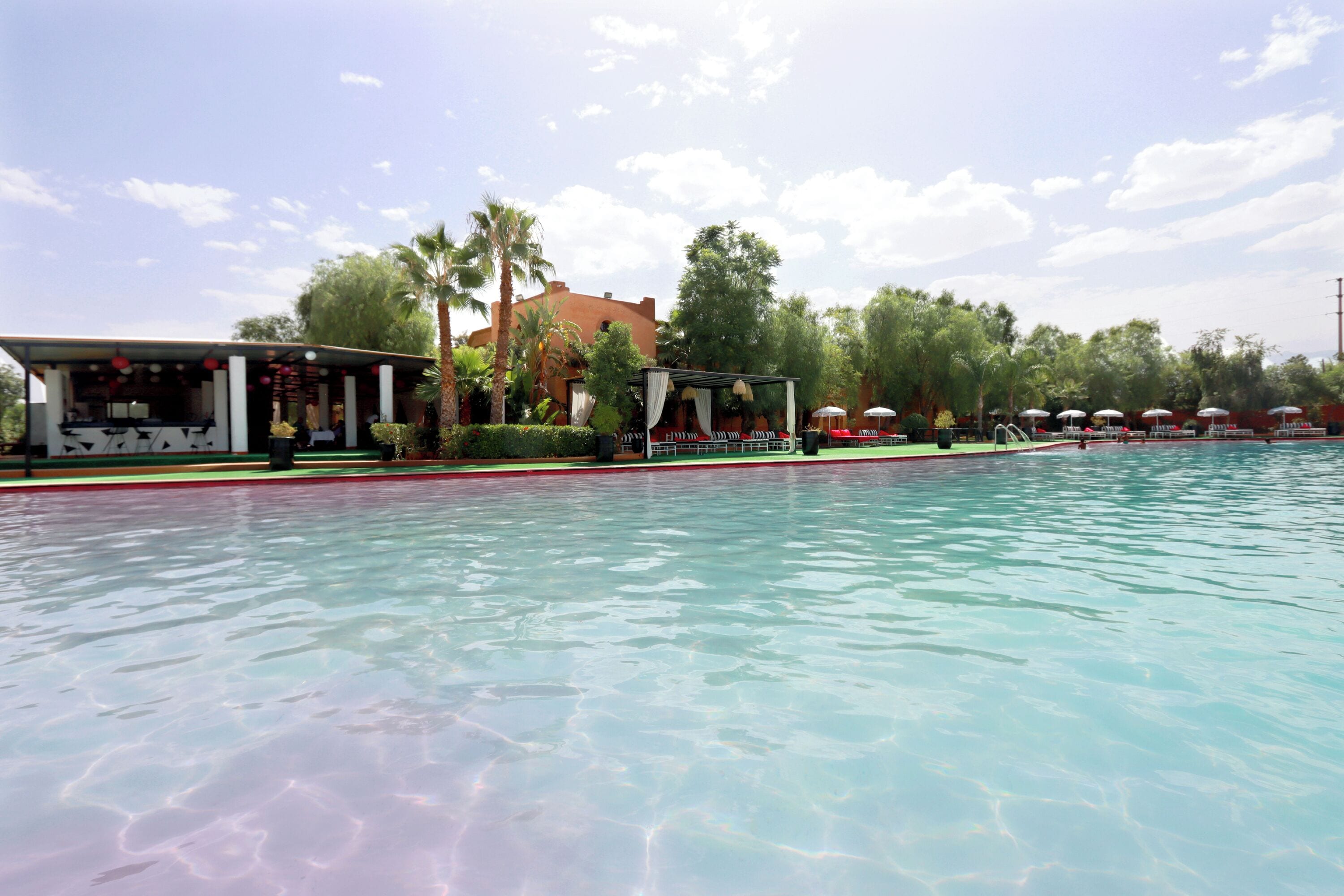 A swimming pool with a covered area and lounge chairs.