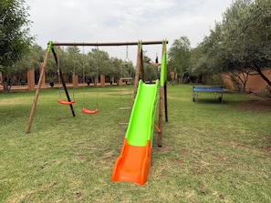 A playground with a slide, swings, and a bench.