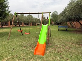 Un parque infantil con tobogán, columpios y un banco.