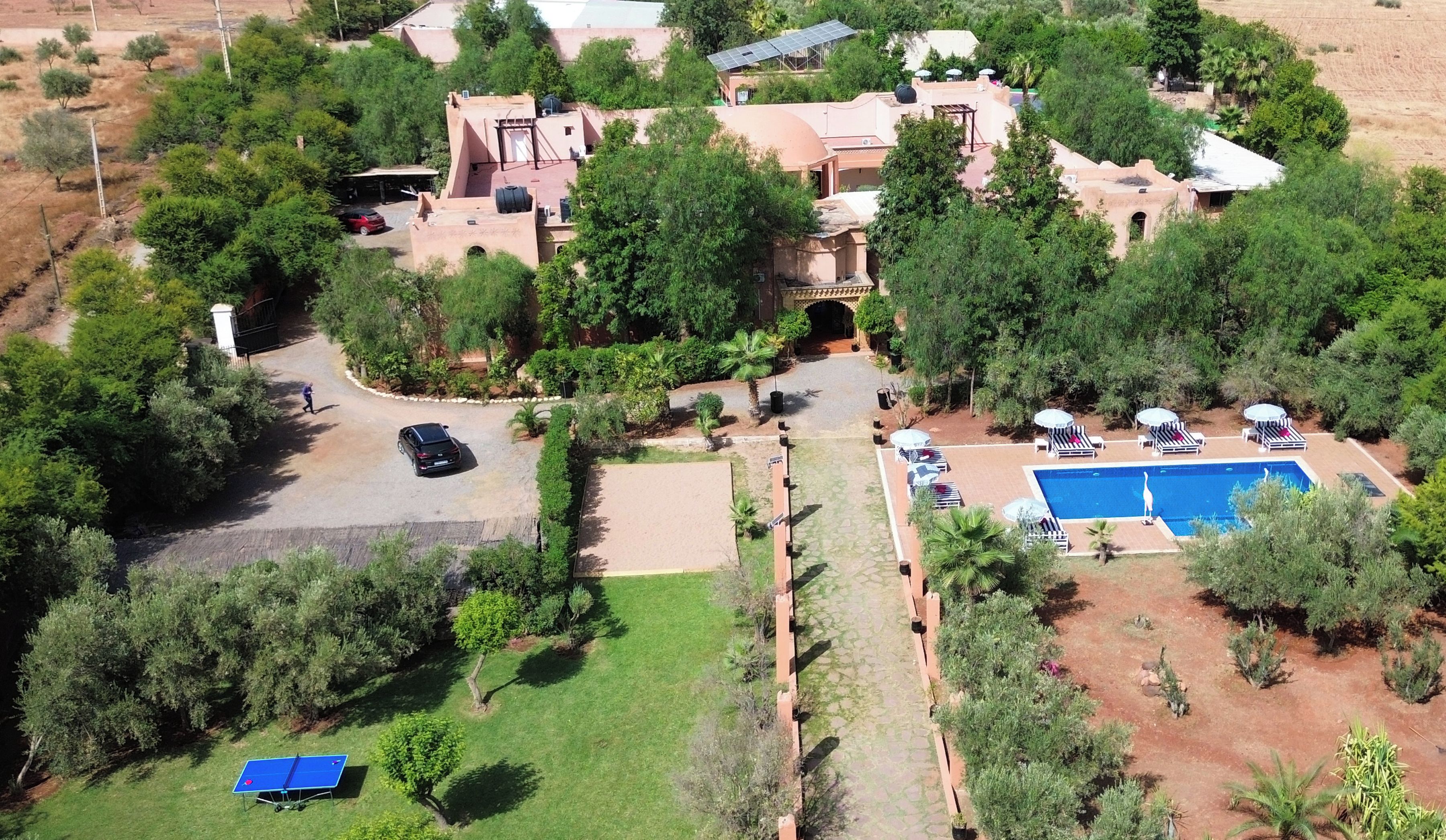 A residential property with a swimming pool, multiple lounge chairs, and a tennis court.
