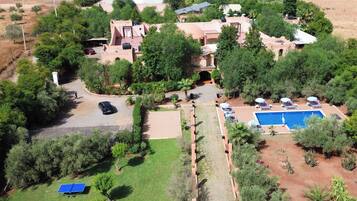 A residential property with a swimming pool, multiple lounge chairs, and a tennis court.
