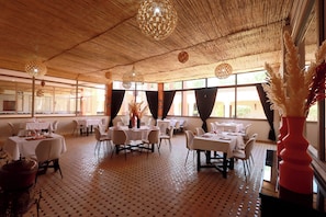 A restaurant with round tables, chairs, and a patterned floor. - HOTEL BOUTIQUE PINK LAGOON (Ghmate)