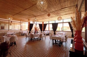 Un restaurante con mesas redondas, sillas y un suelo estampado.