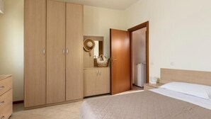 A bedroom with a bed, a wardrobe, a nightstand, and a mirror.