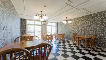 A dining area with checkered flooring, stone walls, and wooden furniture.