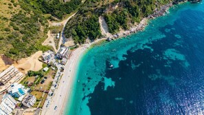 Vista aérea de una zona costera con playa, estacionamiento y edificios.