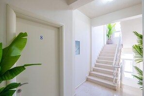 Eine Treppe mit Metallgeländer, eine weiße Tür mit einer Nummer und ein Blumentopf.