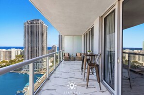 Ein Balkon mit Blick auf das Meer und hohe Gebäude.