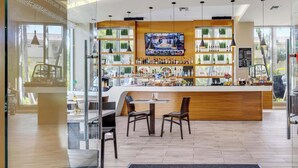 Un espace bar avec un comptoir en bois, des sièges et un écran de télévision.