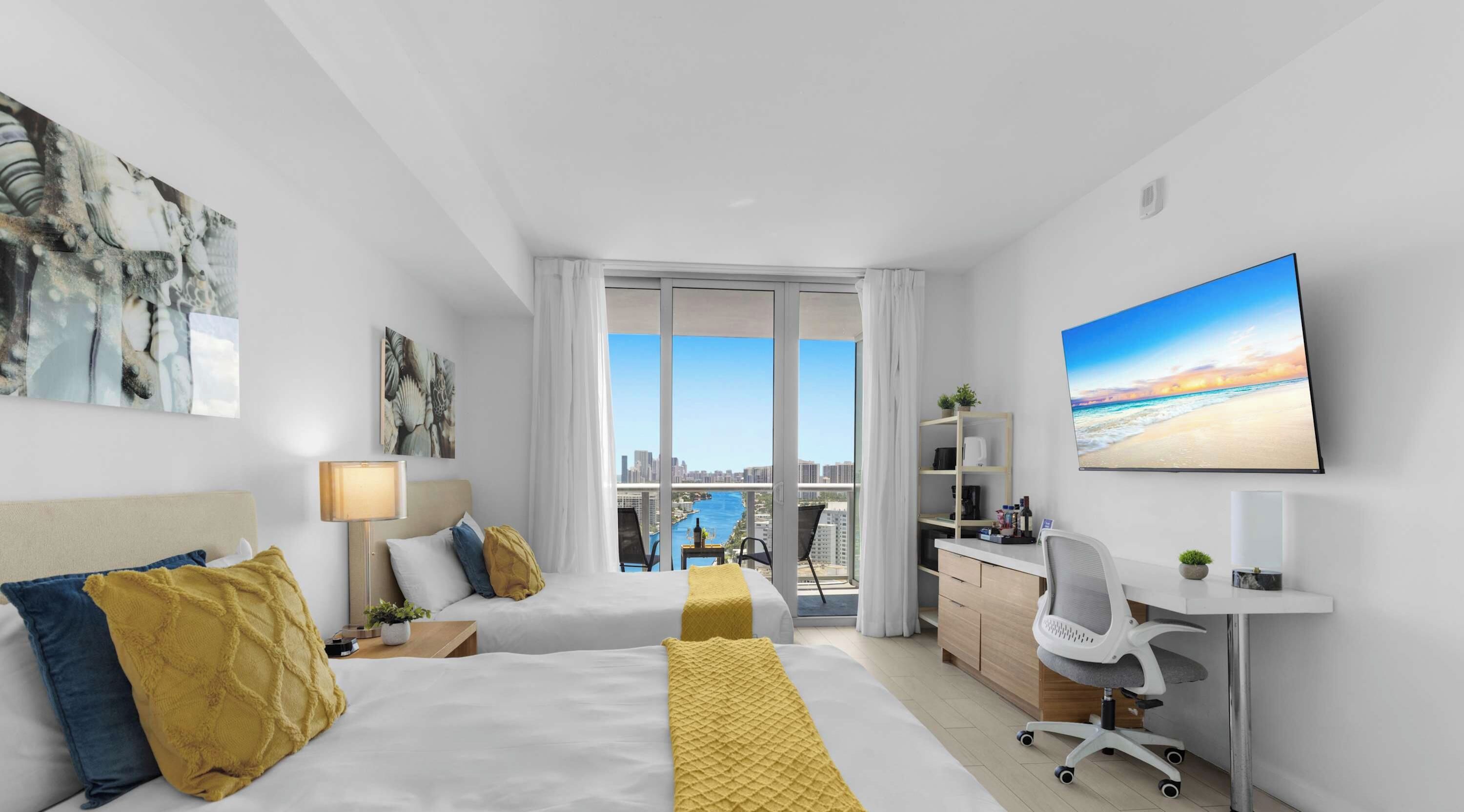Une chambre d’hôtel moderne avec deux lits, un bureau, une chaise et une grande fenêtre donnant sur la ville.