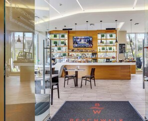 A modern bar area with a TV screen, wooden counter, and seating. - High-Floor Studio | Bay & Miami Skyline (Hallandale Beach)