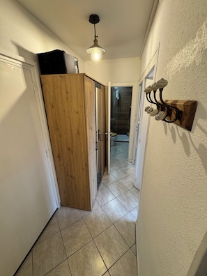 Ein Flur mit einem Holzschrank, einer Deckenleuchte und einer Wandleuchte.