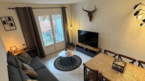 Sala de estar com sofá, televisão, mesa de jantar e decoração de caveira de touro.