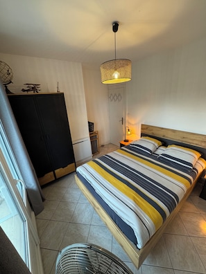 Ein Schlafzimmer mit Bett, Kleiderschrank, einer Tür und einer Deckenleuchte.