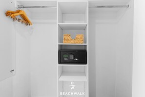 Un placard blanc avec des étagères, une tringle pour suspendre les vêtements et une serrure numérique.