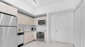 Une cuisine moderne dotée d’appareils électroménagers en acier inoxydable, de meubles blancs et d’un sol carrelé de couleur blanche.