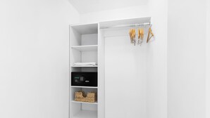 Un armario blanco con estantes, una barra para colgar ropa y un candado digital.