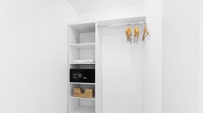 Ein weißer Kleiderschrank mit Regalen, einer Kleiderstange und einem digitalen Schloss.