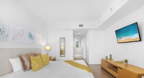 A modern bedroom with a bed, bedside lamp, artwork, and a TV on the wall. - Marina Views  2BR  Beachwalk Resort (Hallandale Beach)