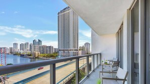 A balcony with a view of a cityscape, including high-rise buildings and a body of water. - Spacious 2BR · Marina View at Beachwalk (Hallandale Beach)
