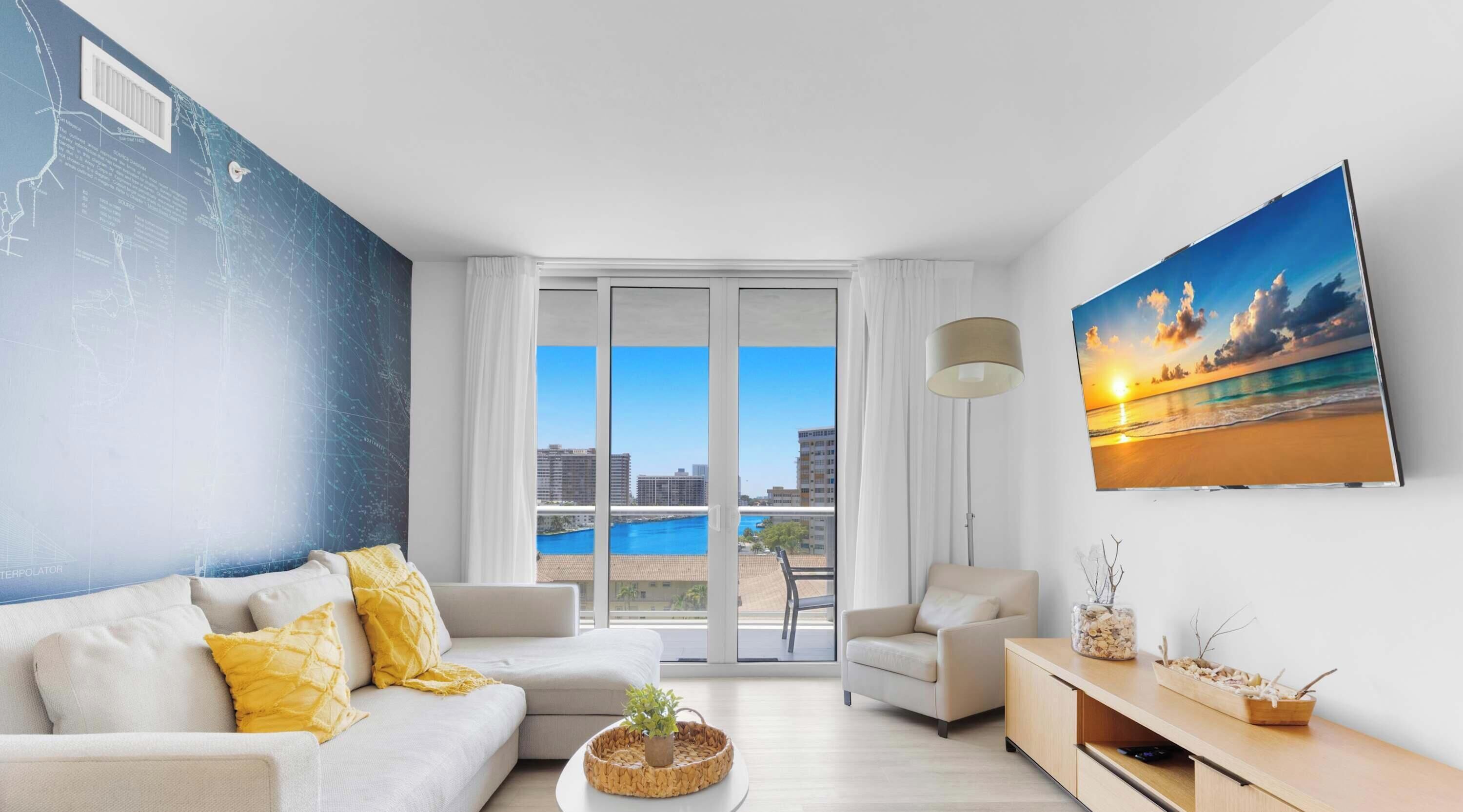 A modern living room with a sofa, armchair, and a painting of a sunset over the ocean.