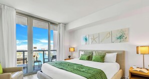 Habitación de hotel con una cama grande, dos lámparas de noche, vistas a la ciudad y un balcón.