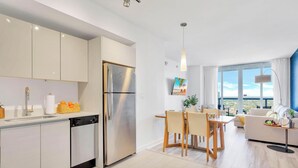 Una cucina moderna con frigorifero in acciaio inossidabile e zona pranzo con tavolo e sedie.
