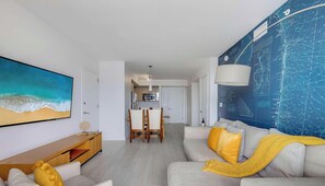 Ein modernes Wohnzimmer mit einem großen Gemälde, einem Essbereich und einer Küche.