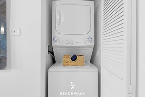 A white washing machine with a basket of clothes on top, a control panel with various settings, and the brand name 'BEACHWALK' on the front. - Waterway View 2BR · Beachwalk Resort (Hallandale Beach)