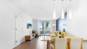 Un salon moderne avec un coin repas, de grandes fenêtres et une vue sur l’extérieur.