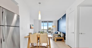 A modern kitchen with a stainless steel refrigerator, wooden dining table, and chairs. - Beachwalk 1BR  Pininfarina Design & Pool (Hallandale Beach)