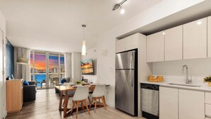 A modern kitchen with stainless steel appliances, a dining area with a view, and a living space with a large window. - Stunning 1BR · Gym & Resort Pool (Hallandale Beach)