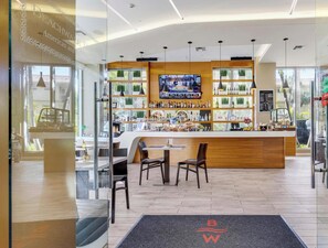 Zona de bar con televisor, estantes con botellas y asientos.