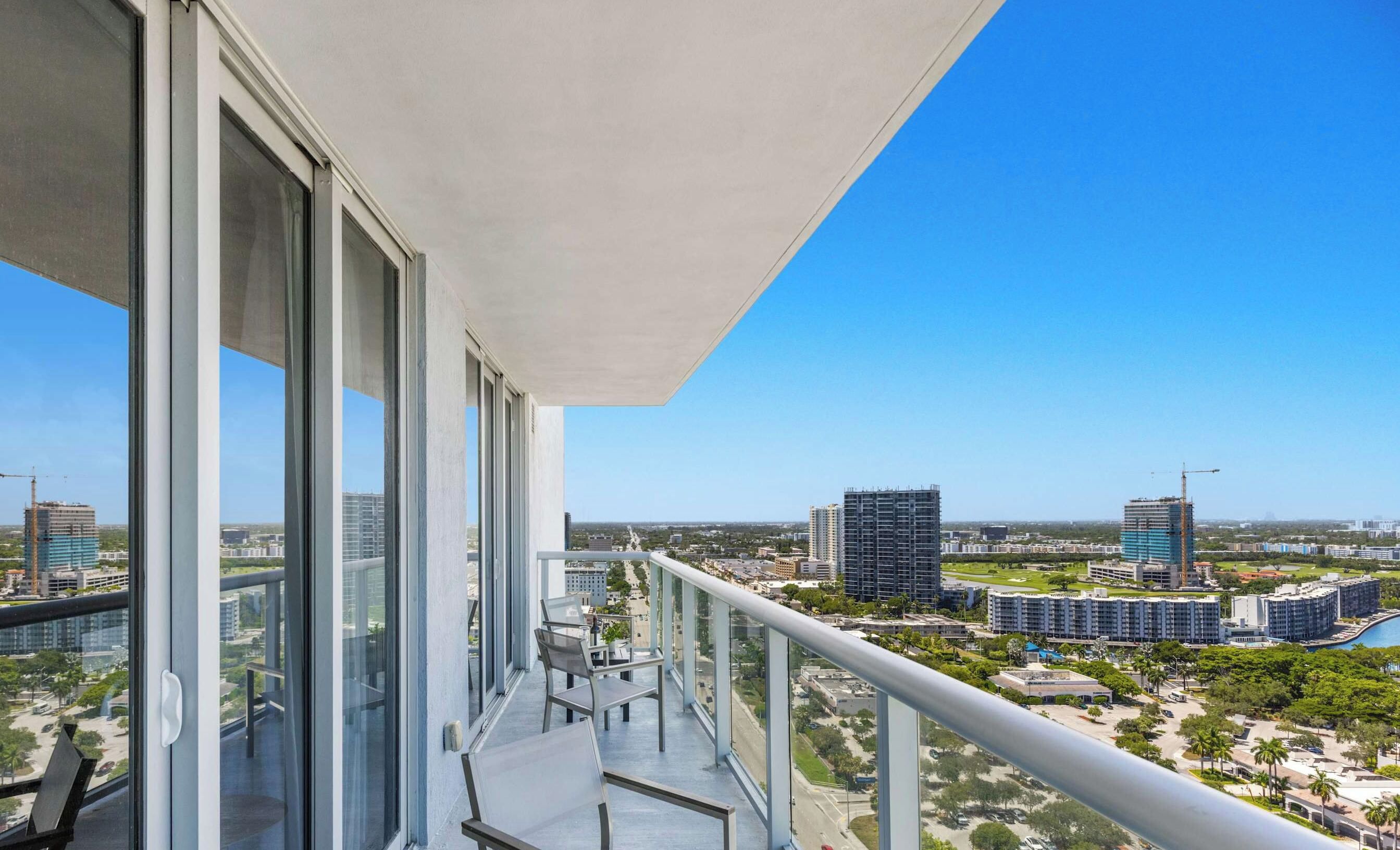 A balcony with a clear view of a cityscape, including high-rise buildings and construction cranes.