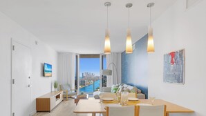 A modern dining area with a view of a city skyline and a pool. - Bright Apt w/ Intracoastal View | Beach Shuttle (Hallandale Beach)