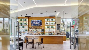 A bar area with a wooden counter, seating, and a TV screen. - Bright Apt w/ Intracoastal View | Beach Shuttle (Hallandale Beach)
