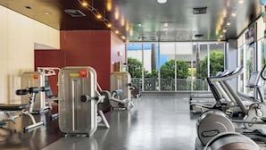 Un gimnàs amb màquines de cardio, màquines de musculació i un gran finestral amb vista a zones verdes.