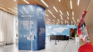 Eine moderne Lobby mit einer Rezeption, einem blauen Infostand und einer Weltkarte an der Wand.