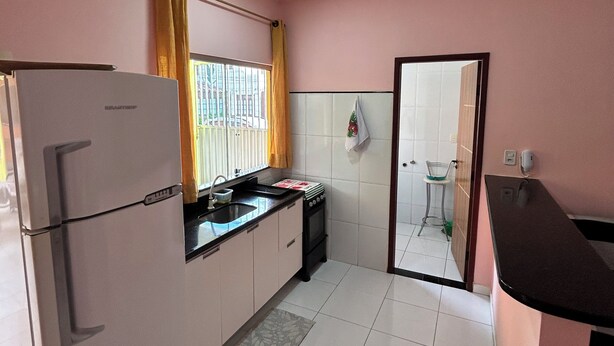 Una cucina con frigorifero, piano cottura, lavello e finestra con tende.