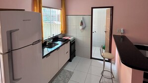 Una cucina con frigorifero, fornello, lavello e una sedia.