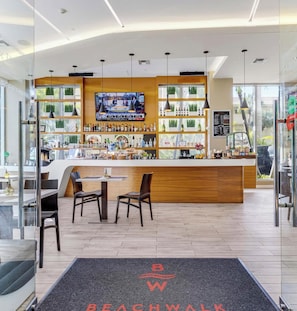 A modern bar area with a TV screen, wooden counter, and seating. - Elegant 2BR Condo · Beachwalk Resort Pool (Hallandale Beach)