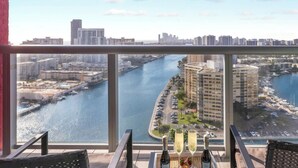 A balcony with a city view overlooking a river, a marina, and high-rise buildings. - Sunset Condo 2BR · Beachwalk Resort Florida (Hallandale Beach)