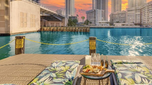 A waterfront dining area with a view of the city skyline, a dock, and caution signs. - Sunset Condo 2BR · Beachwalk Resort Florida (Hallandale Beach)