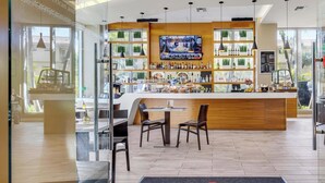 A bar area with a wooden counter, seating, and a TV screen. - Sunset Condo 2BR · Beachwalk Resort Florida (Hallandale Beach)